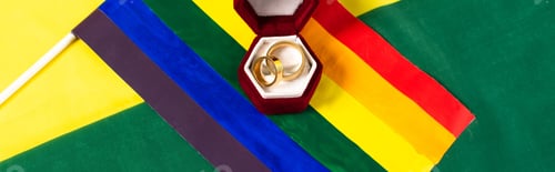 Preview: top view of lgbt flag and jewelry box with wedding rings on rainbow colors background, banner