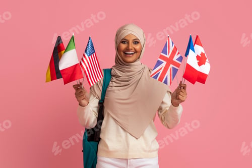 Preview: Study Abroad. Smiling Muslim Woman In Hijab Holding International Flags And Backpack