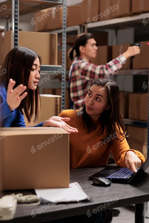 Preview: Warehouse operator supervising coworker doing inventory on laptop