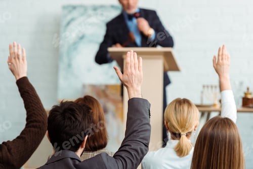 Preview: back view of buyers raising hands to auctioneer during auction