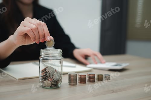Vista previa: Un primer plano de una mujer de negocios poniendo una moneda en un tarro de vidrio Para ahorrar dinero y planificarlo un