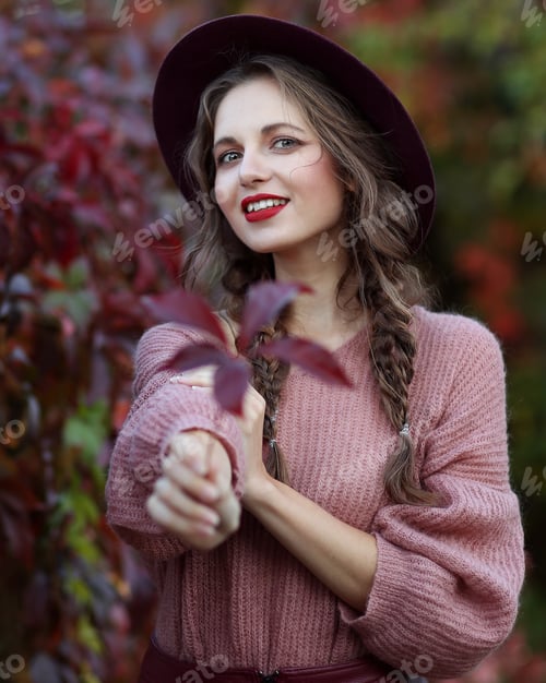 Preview: portrait of a beautiful girl on a background of autumn leaves with a leaf in her hand
