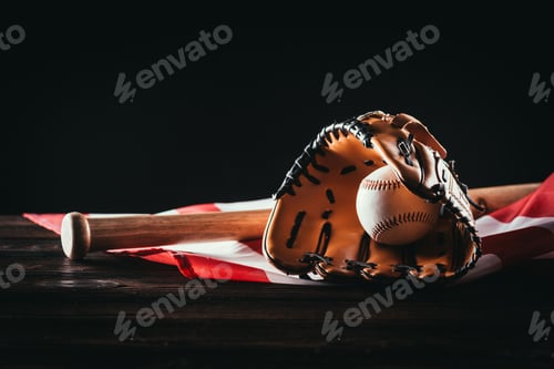 Preview: close-up view of baseball glove with ball and bat on wooden table and us flag on black