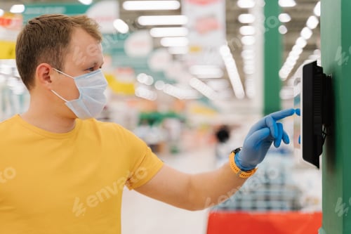 Preview: Young man types on touch screen of self checkout, wears protective rubber blue gloves