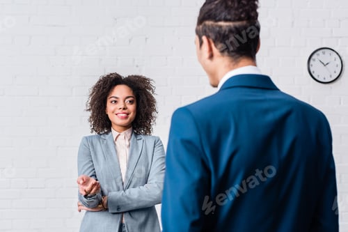 Preview: African american businesswoman talking to businessman on white wall background