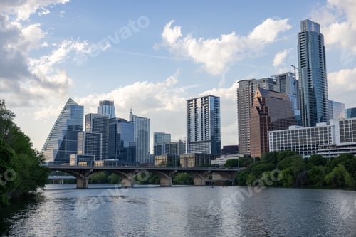 Preview: Of several tall buildings in the distance behind the water and trees