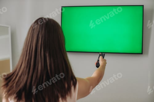 Preview: A girl with a remote control in her hands switches channels.