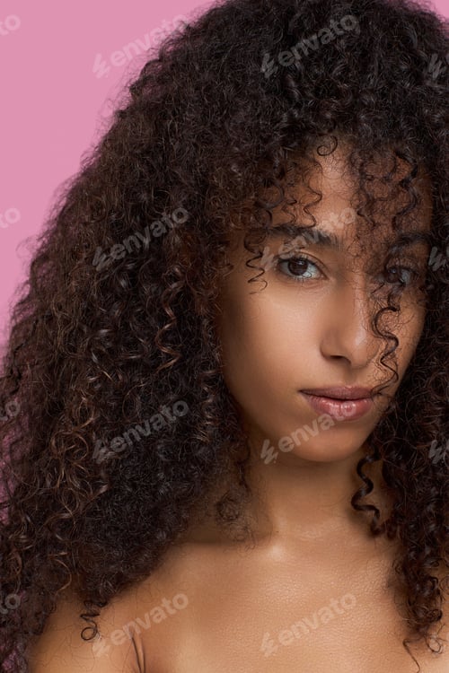Preview: Portrait of Young Adult Black Woman Gazing Confidently Against Pink Background