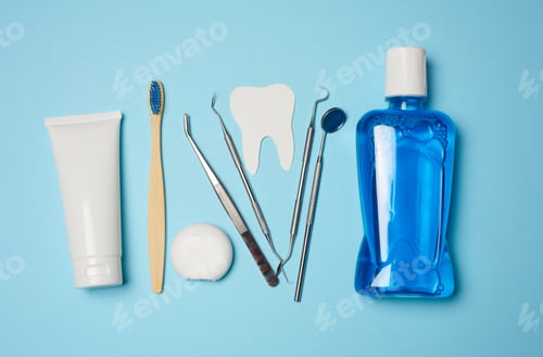 Preview: Mouthwash, toothpaste tube, dental floss and medical mirror on a blue background, oral hygiene.