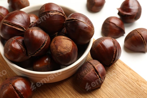 Preview: Bowl with roasted edible sweet chestnuts on white table, closeup