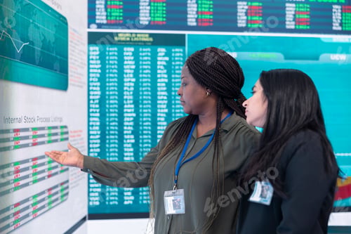 Preview: Diverse team of employees examine infographics on a big screen