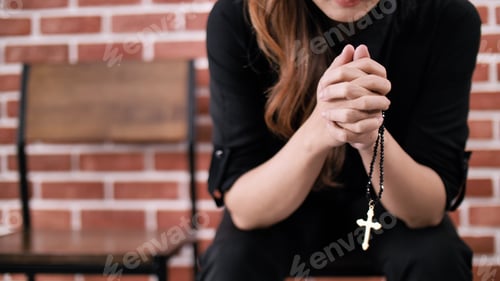 Preview: A young Asian Christian woman praying to Jesus Christ in a church.