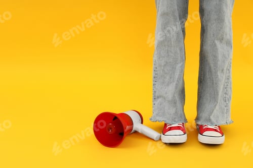 Preview: Female legs and megaphone on yellow background