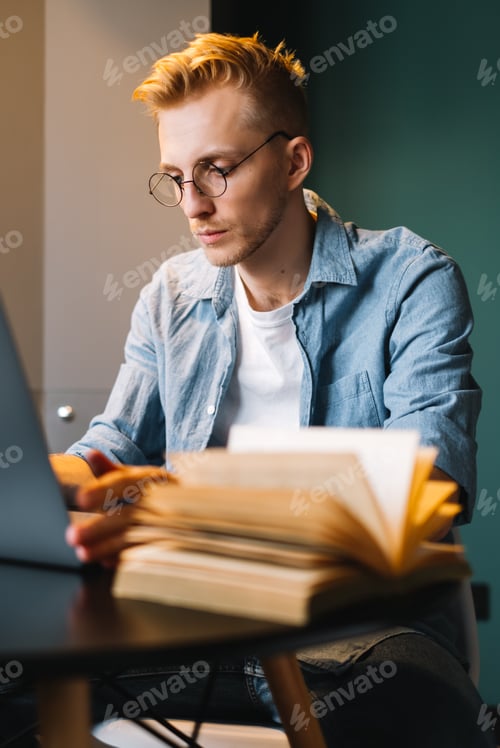 Preview: Caucasian man college student in glasses studying with laptop distantly preparing for test exam