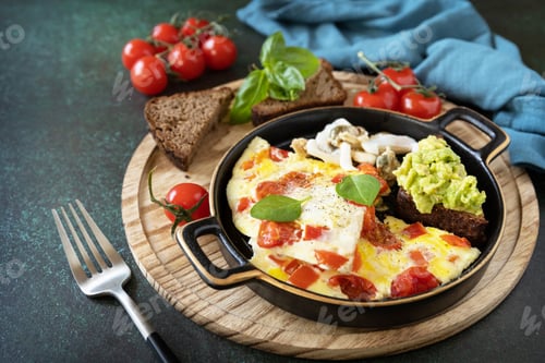 Aperçu: Omelette or omelet with sweet peppers and tomatoes, toasts bread with avocado.