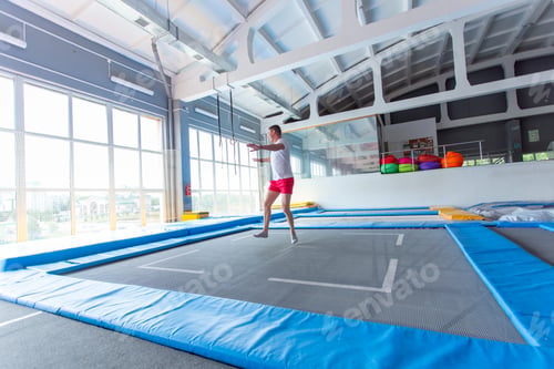 Preview: Fitness, fun, leisure and sport activity concept - Handsome happy man jumping on a trampoline