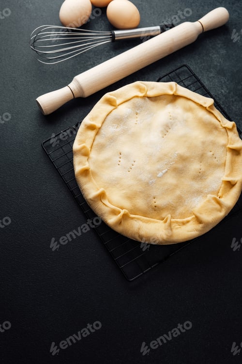 Preview: Homemade pie crust preparation on black countertop with baking tools