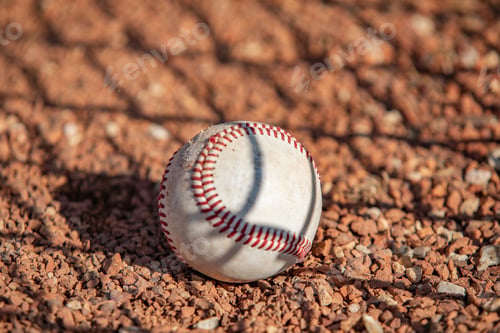 Preview: Closeup of a baseball laying in the red clay on the field