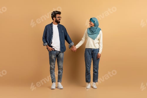 Preview: Full length portrait of young muslim couple smiling and looking at each othe
