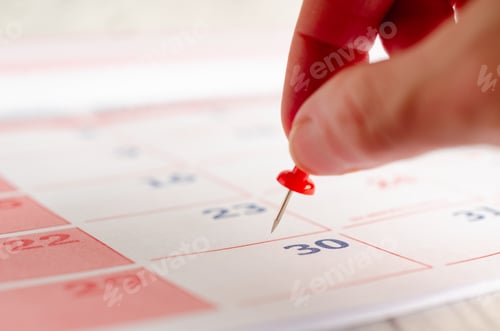 Preview: A person putting a red thumbtack on a calendar page.