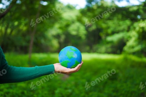 Preview: An Asian woman holds a globe in green forest,symbolizing importance preserving nature.emphasizes