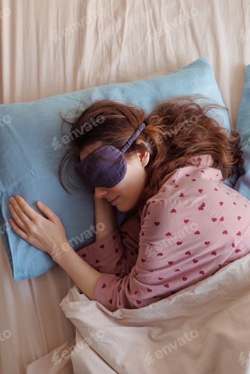 Preview: happy woman in bed wakes up, person in sleep mask stretches and yawns and enjoys her morning