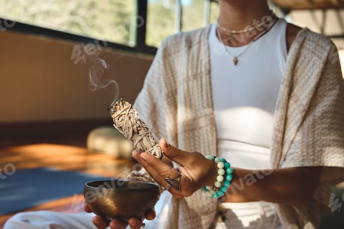 Preview: Yogi woman holding scented herbal stick in hand doing yoga meditation exercises.