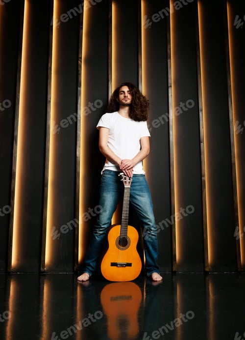 Preview: Hispanic Guy Posing With Guitar Standing In Black Studio Interior