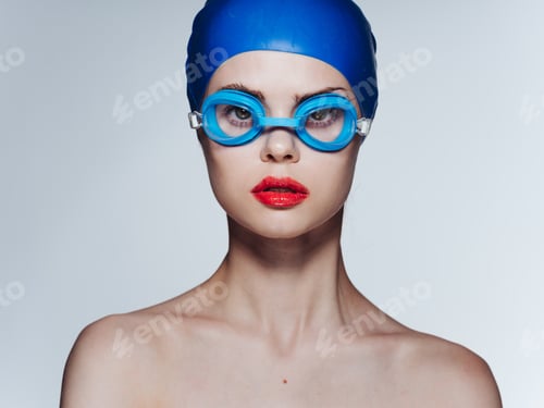Preview: Woman in blue goggles swimming cap naked shoulders light background