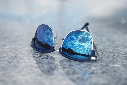 Preview: Sunglasses with reflection of the blue sky in glass. Selective focus photo.