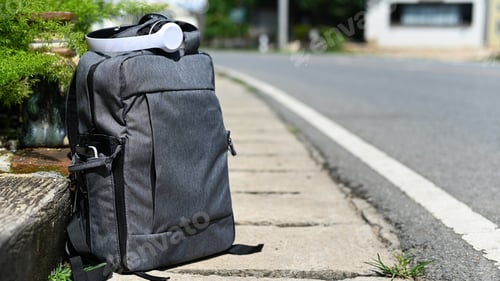Preview: Tourist backpack and headphones on the road while waiting for the car, Travel concept.
