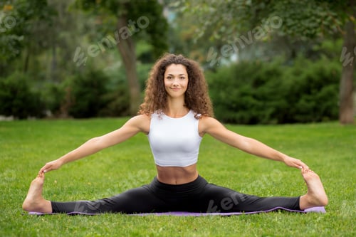 Preview: Smiling Pretty Woman Doing Yoga Exercises Sitting In The Splits. Green Grass Background