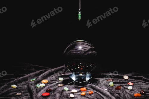 Preview: fortune telling stone above crystal ball on black velvet cloth isolated on black