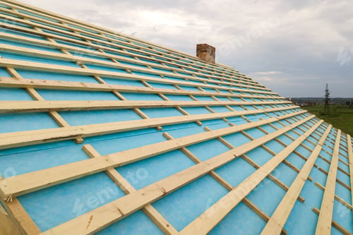 Preview: Brick house with wooden roof frame under construction.