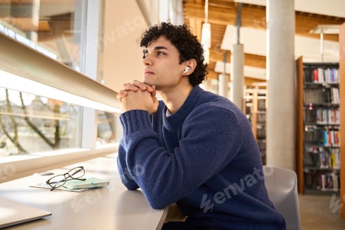 Preview: Hispanic student attentively listens to a broadcasted online lesson on earphones, in library campus