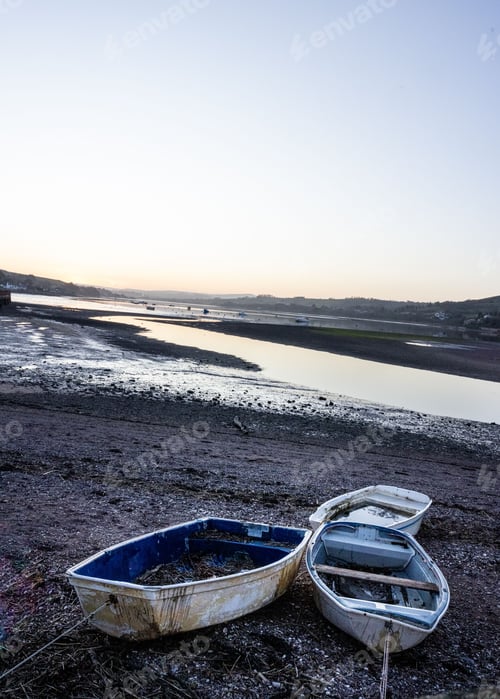 Preview: Serene sunrise over a river with abandoned boats