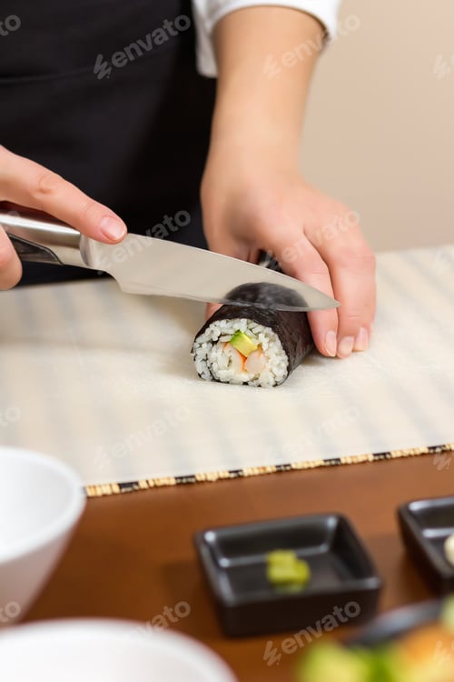 Preview: Closeup of woman chef cutting japanese sushi roll