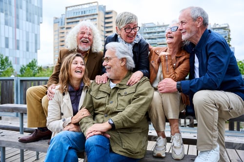 Preview: Group of elderly Caucasians friends people having fun laughing together sitting on bench in city.