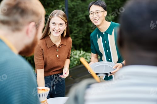 Preview: Cheerful Friends Setting Table Outdoors