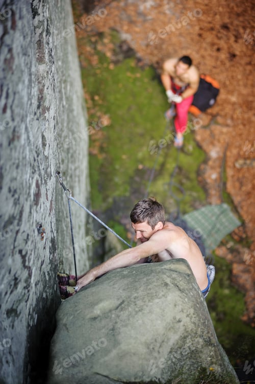 Preview: Muscular rock climber climbs on cliff wall with rope