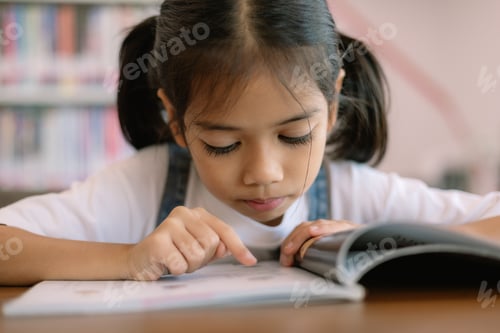 Preview: A young girl is reading a book and pointing to a word