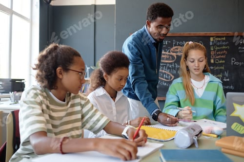 Preview: Black Male Teacher Helping Group of Teen Students at Lesson in Class