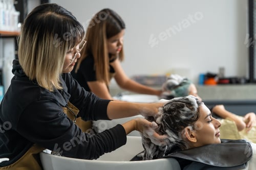 Preview: Asian expert Hairdresser massaging and washing hair of young customers.