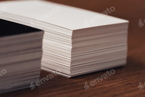 Preview: selective focus of stacked white and black empty business cards on brown wooden surface