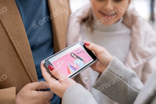 Preview: Female hands holding smartphone with home page of online shop