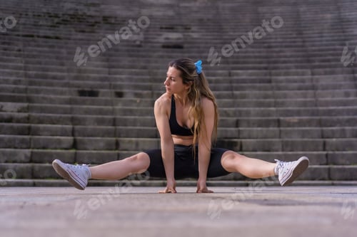 Preview: Caucasian young woman doing fitness in a city park, doing the splits and rising up in the air