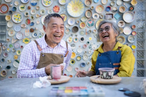 Preview: Asian retired couple is engaged in pottery making and clay painting activities.