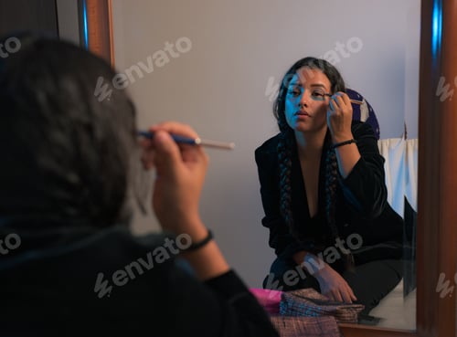 Preview: Young woman applies makeup in front of a mirror