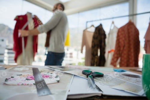 Preview: Equipment and designs on table with designer working in background