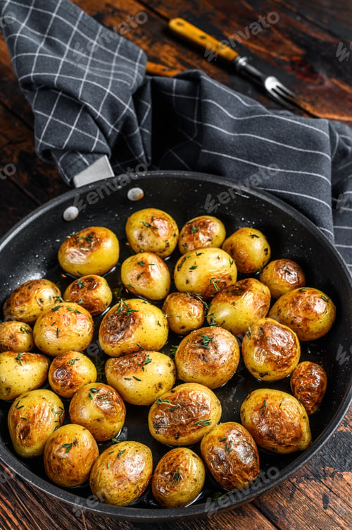 Preview: Roasted potato in frying pan. Dark wooden background. Top view